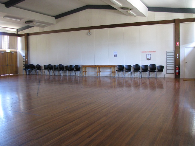 Pearce Community Centre main hall - view across a wooden floor towards chairs and tables at the back of the room